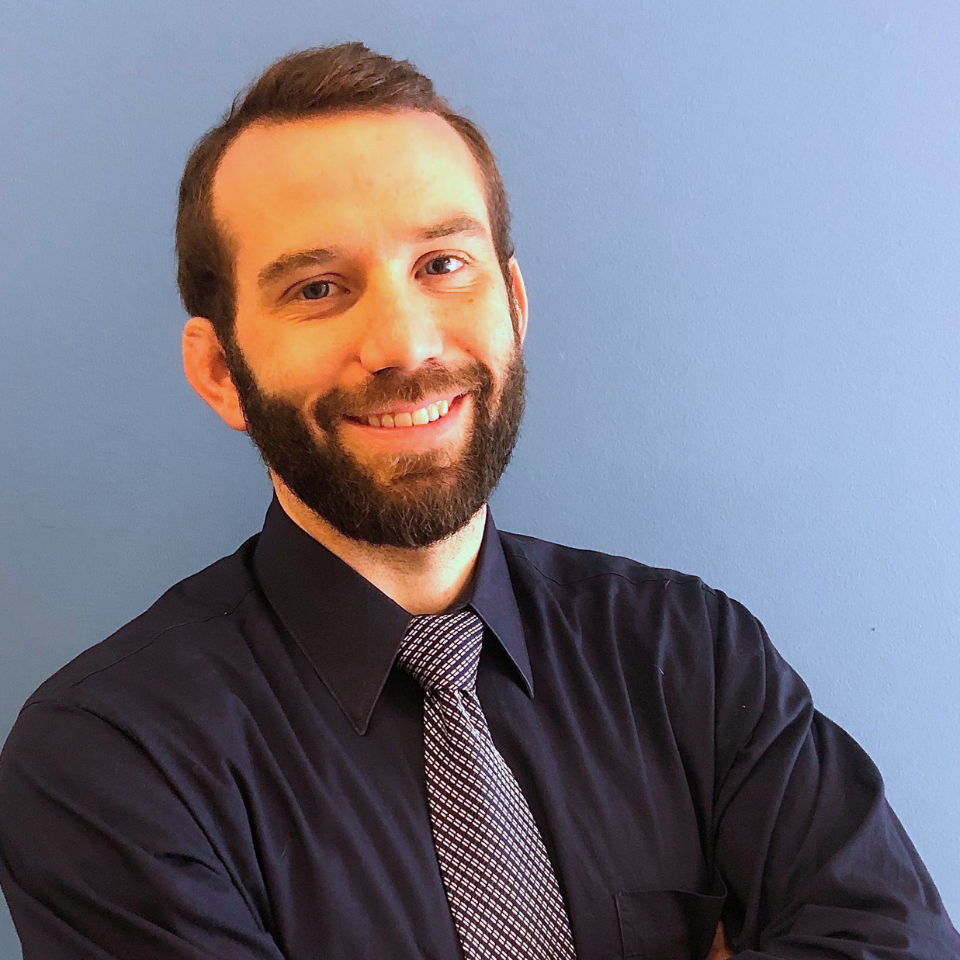 A man with a beard wearing a black shirt and tie