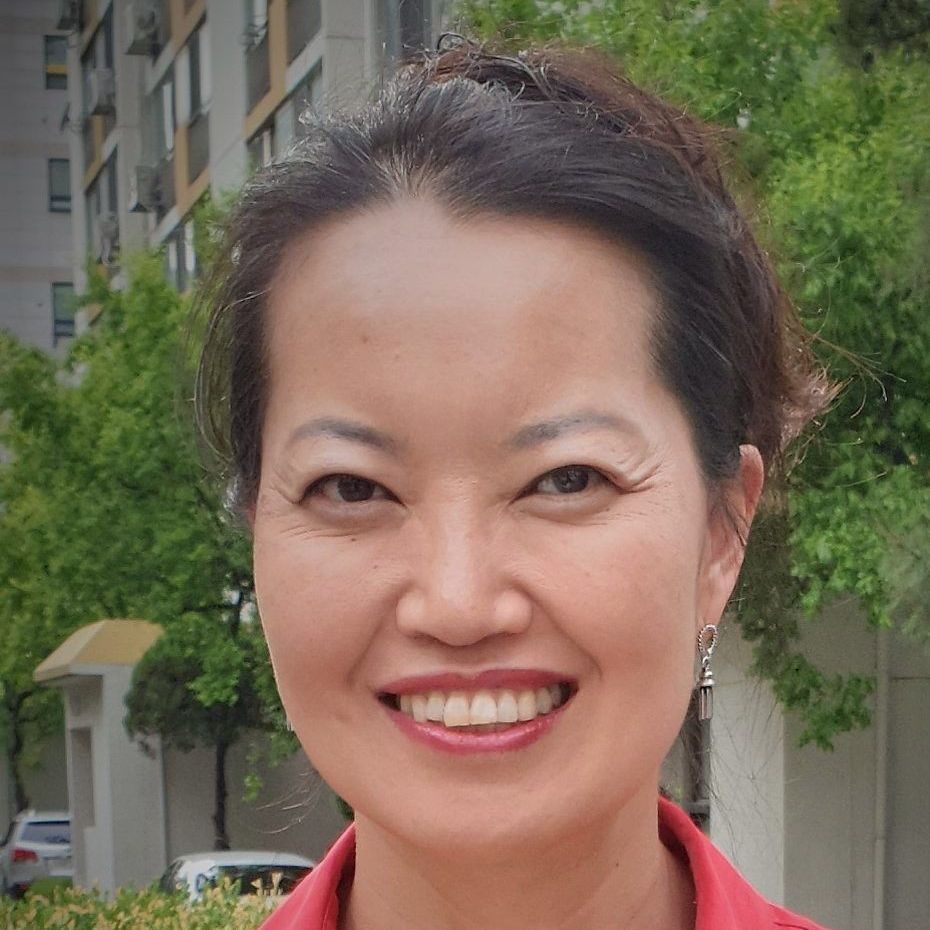 A woman in a red shirt is smiling for the camera.