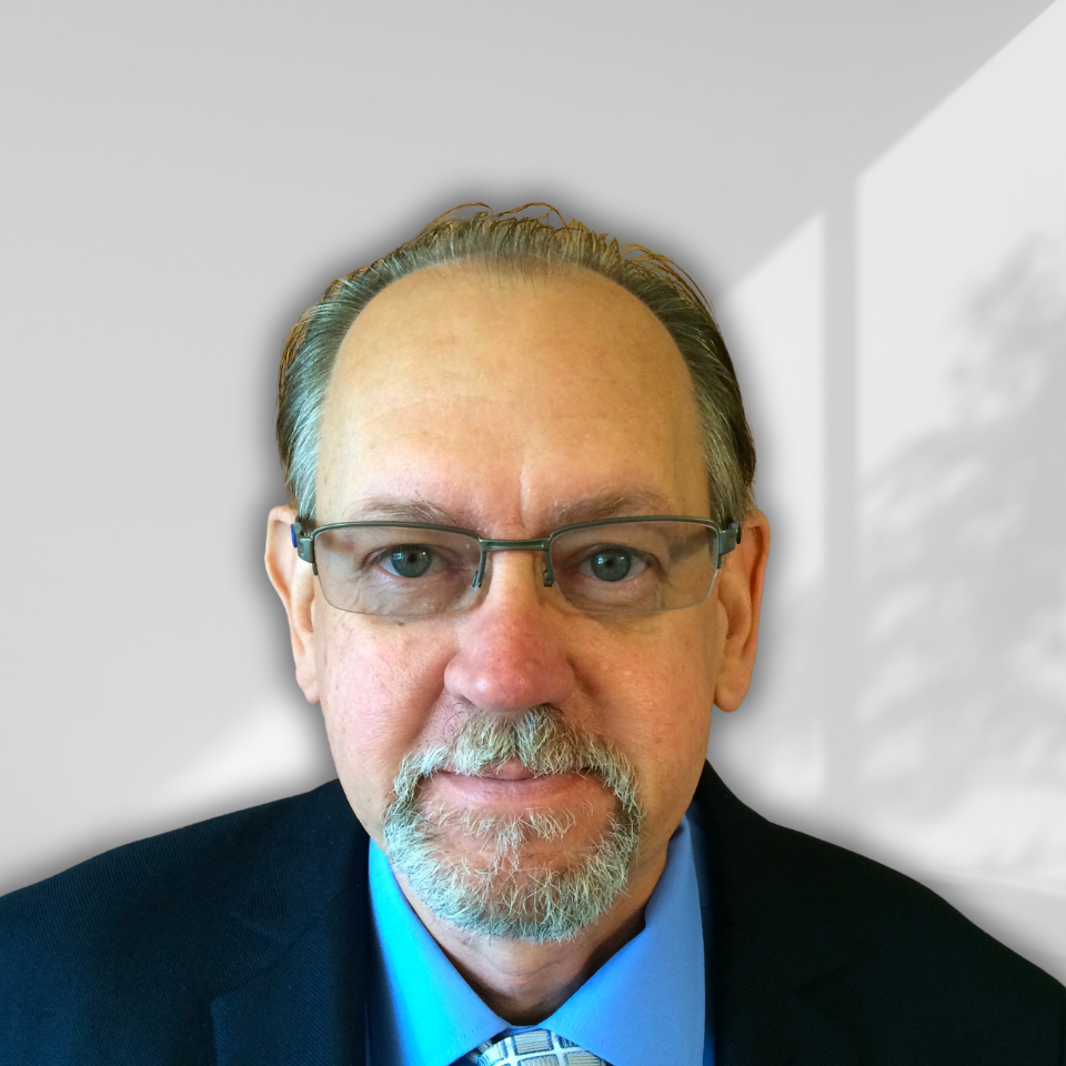 A man with glasses and a beard is wearing a suit and tie