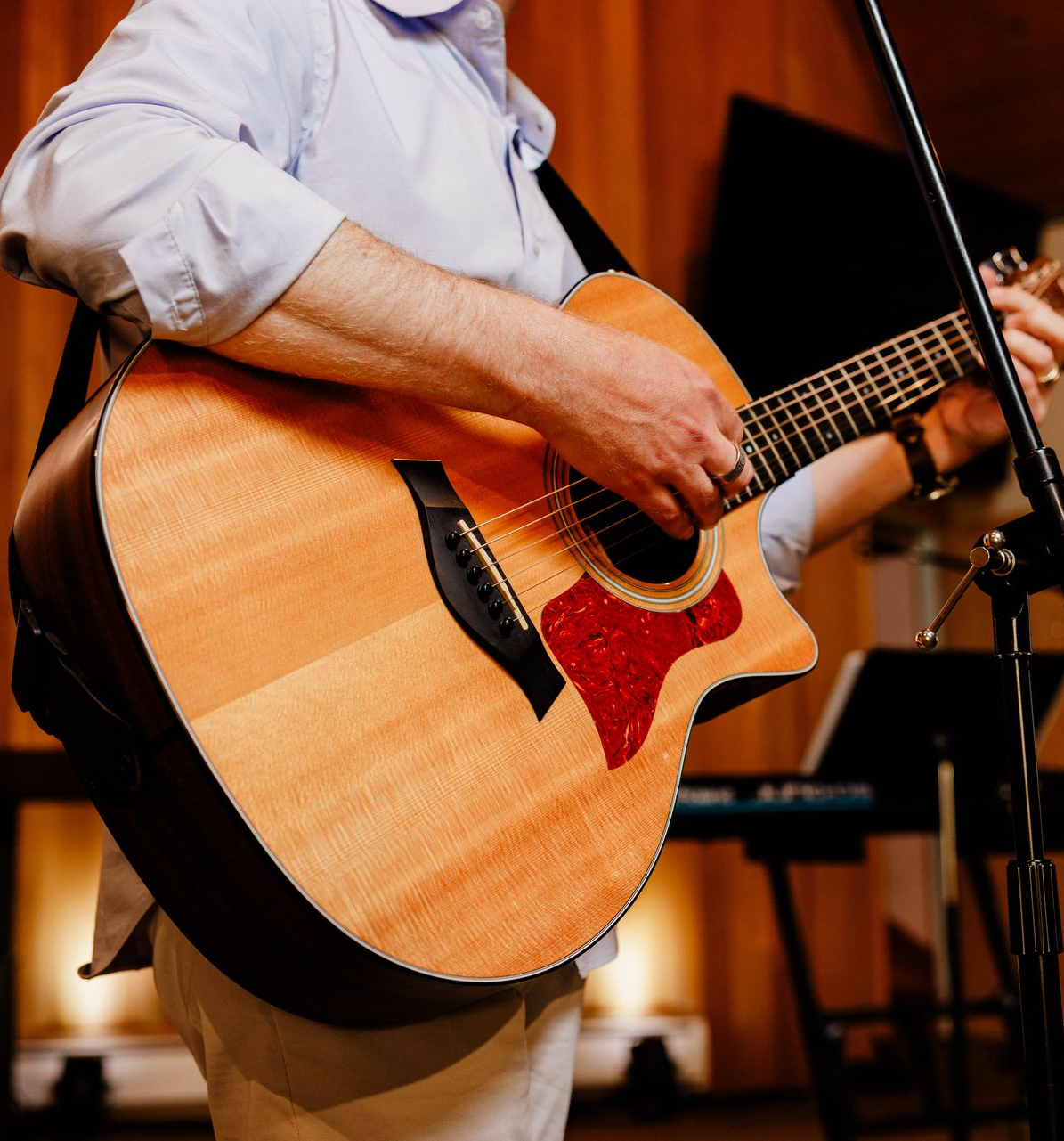 Person playing a natural wood acoustic guitar on stage