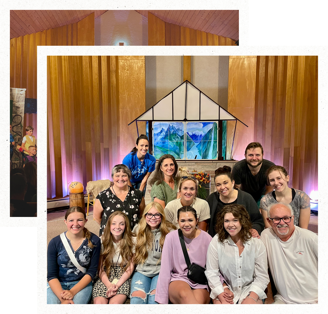 Group of people posing in a church-like hall with wood paneling and a stained-glass backdrop
