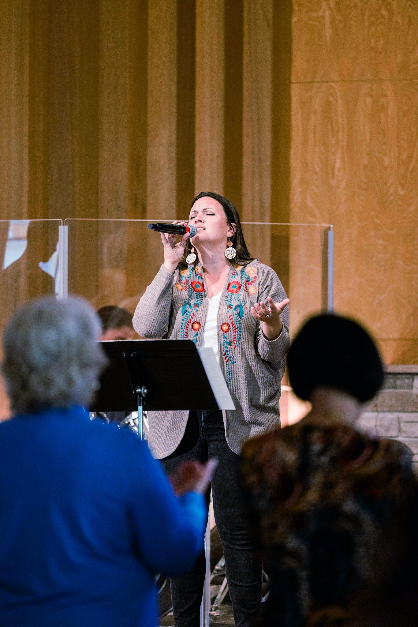 Woman singing into a microphone while playing a keyboard on stage