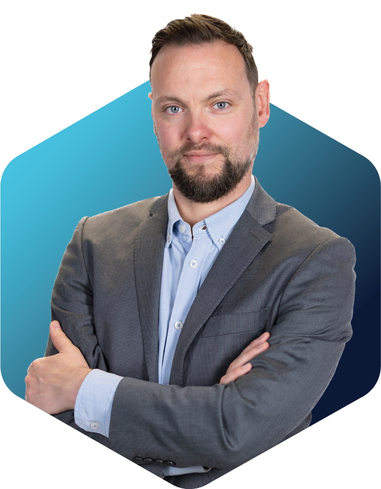 Portrait of a man in a gray blazer and blue shirt with arms crossed against a blue background