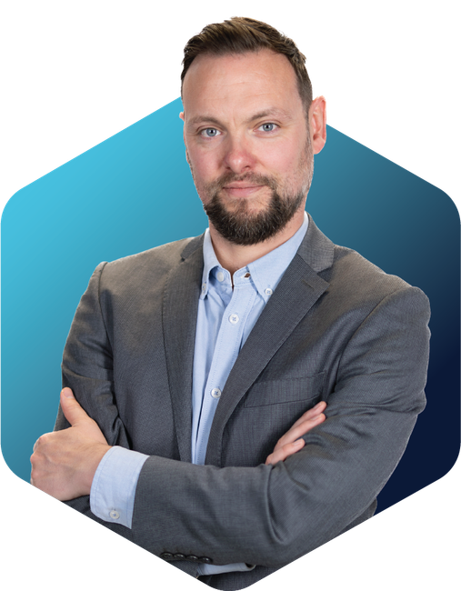 Portrait of a man in a gray blazer and blue shirt with arms crossed against a blue background