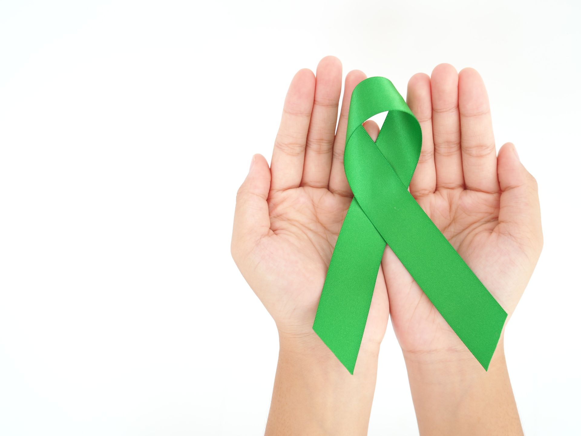 Hands holding a green awareness ribbon on a white background