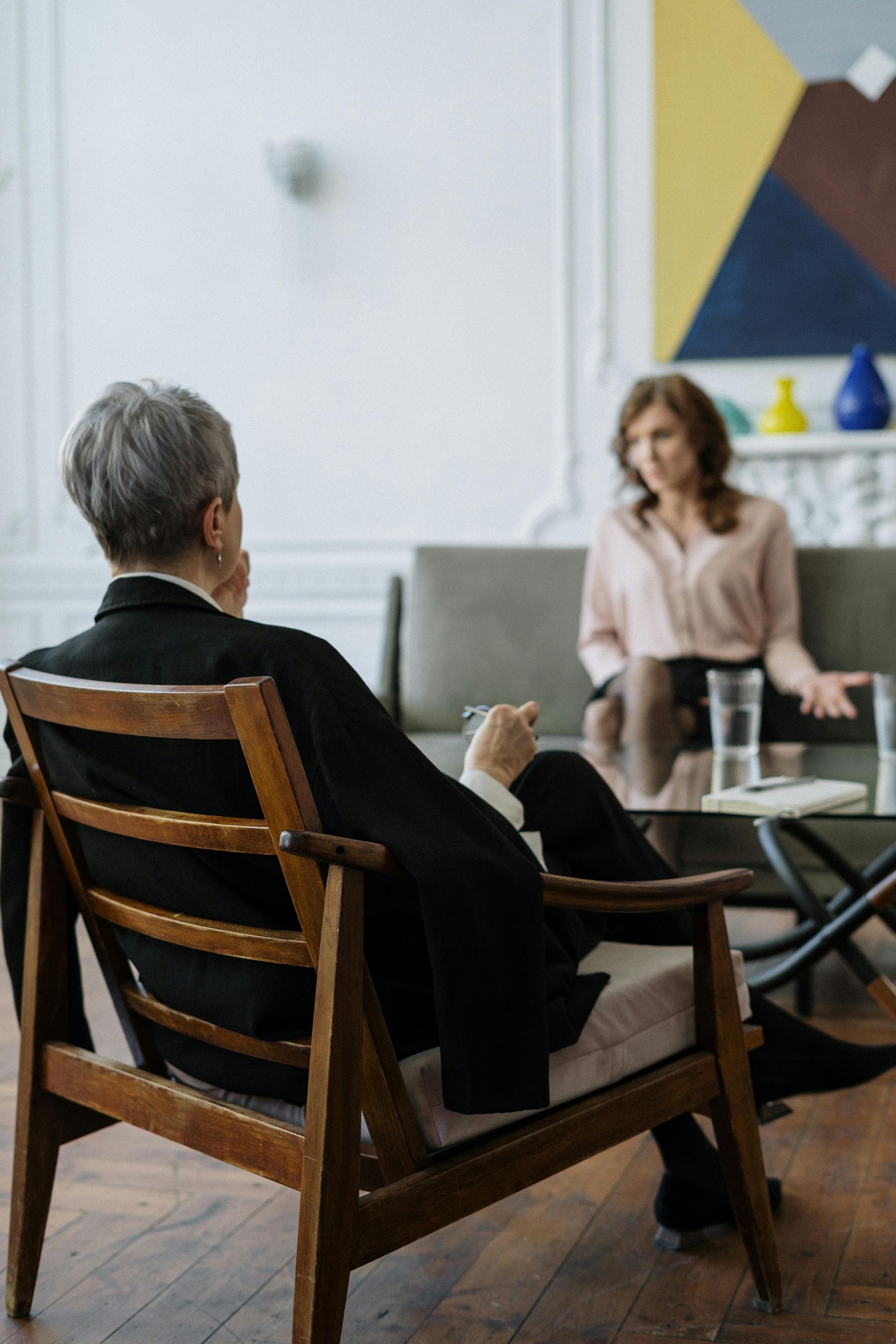 A man is sitting in a chair talking to a woman.