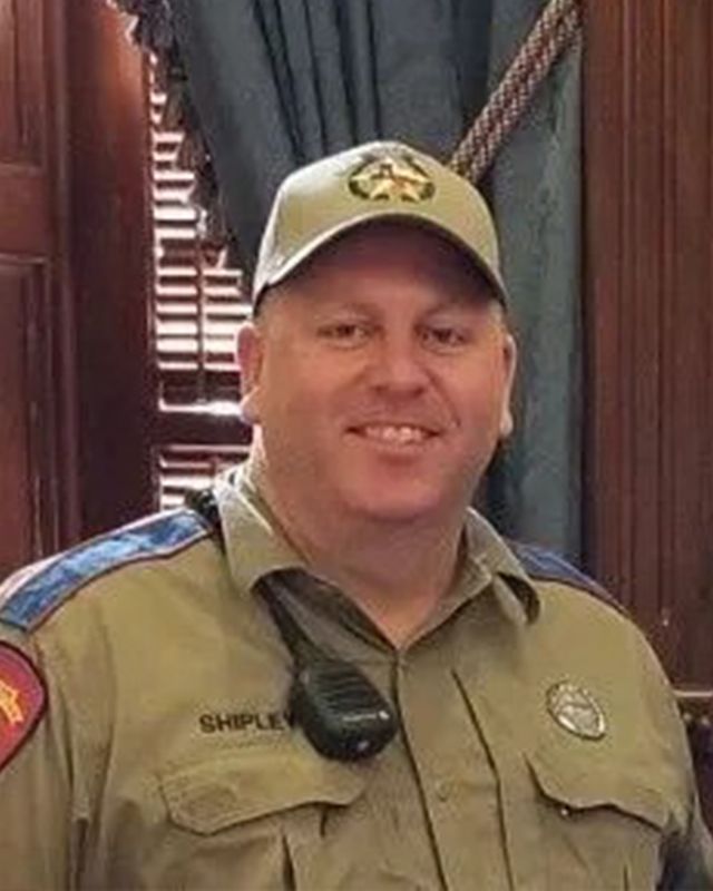 A man in a sheriff 's uniform and hat is smiling for the camera.