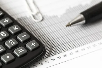 A calculator is sitting on top of a graph next to a pen