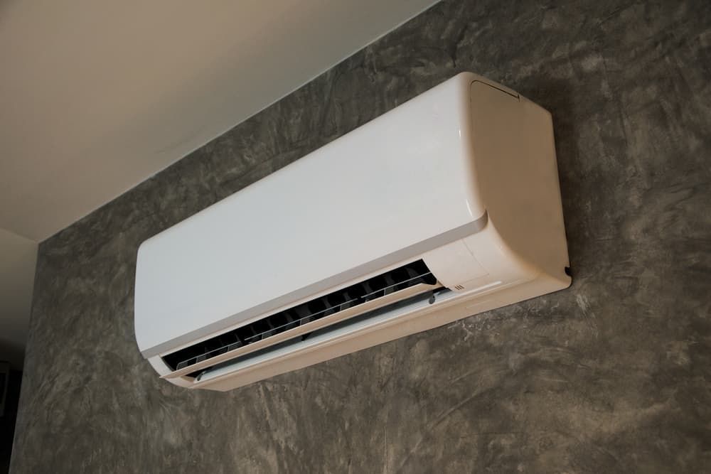 White air conditioner mounted on a gray textured wall.