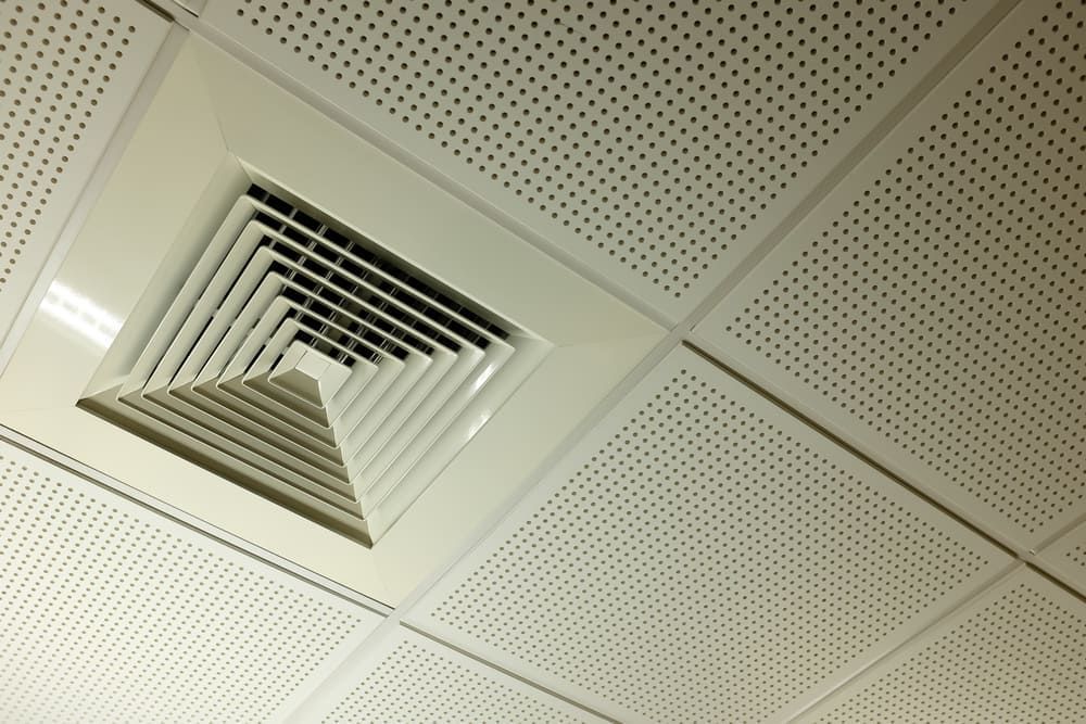 White, perforated ceiling with a square air vent.