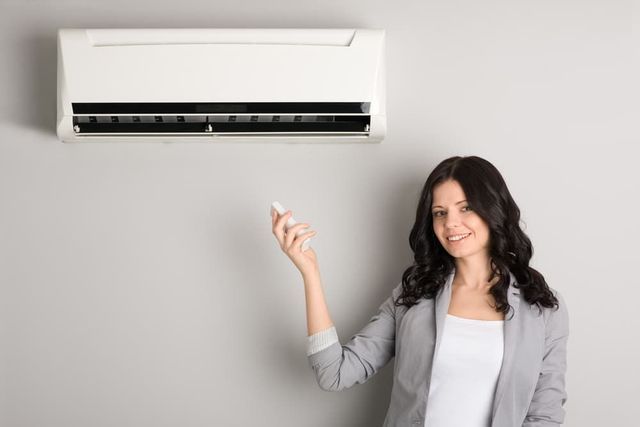 Four white air conditioning units mounted on a wall, with visible fan blades and blue coils.