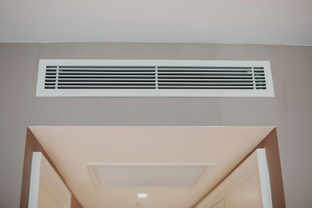 White rectangular air vent above a doorway in a room with gray walls.