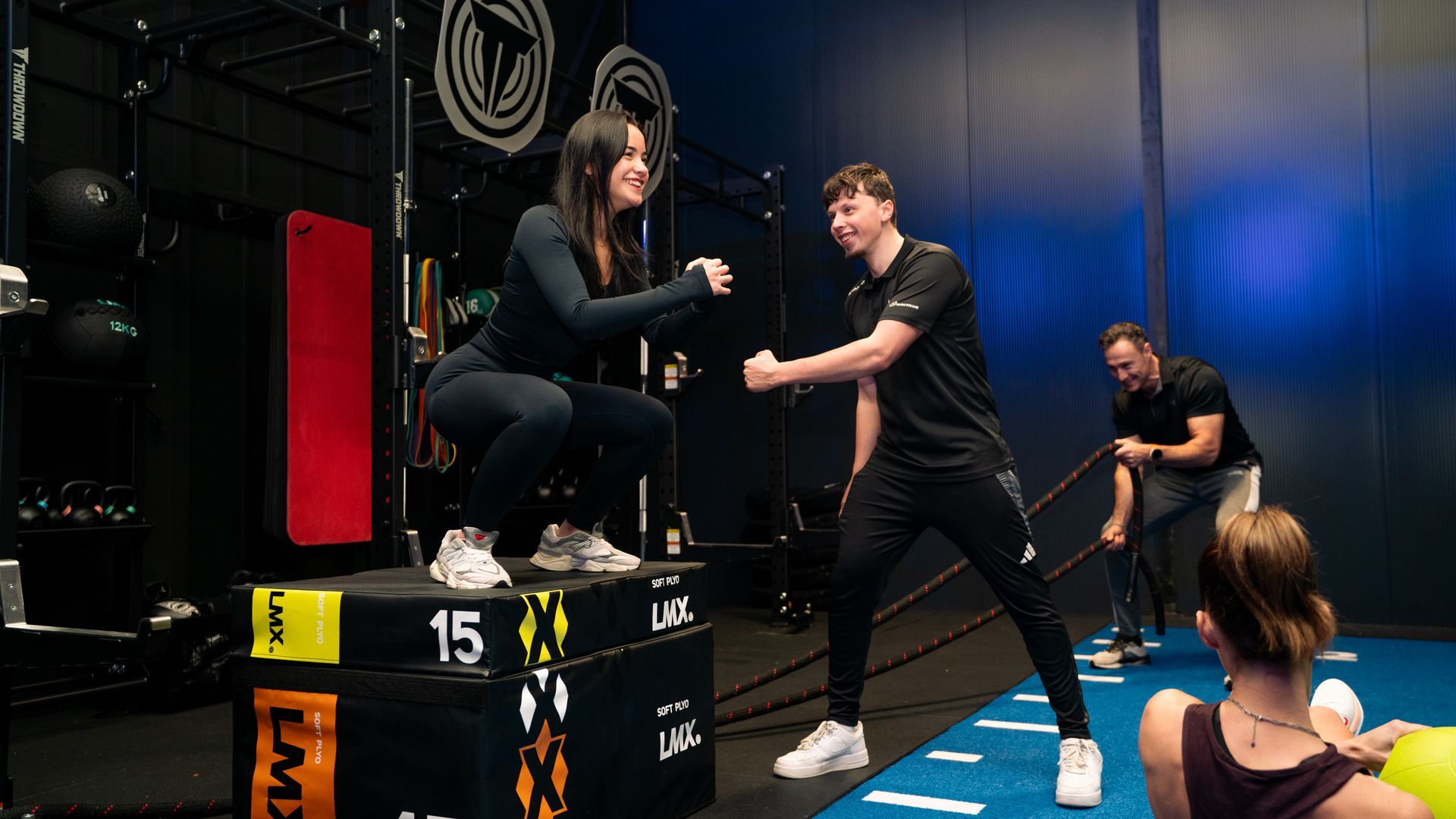 Fitnessles met een trainer die een vrouw helpt haar evenwicht te bewaren op gestapelde boxen/