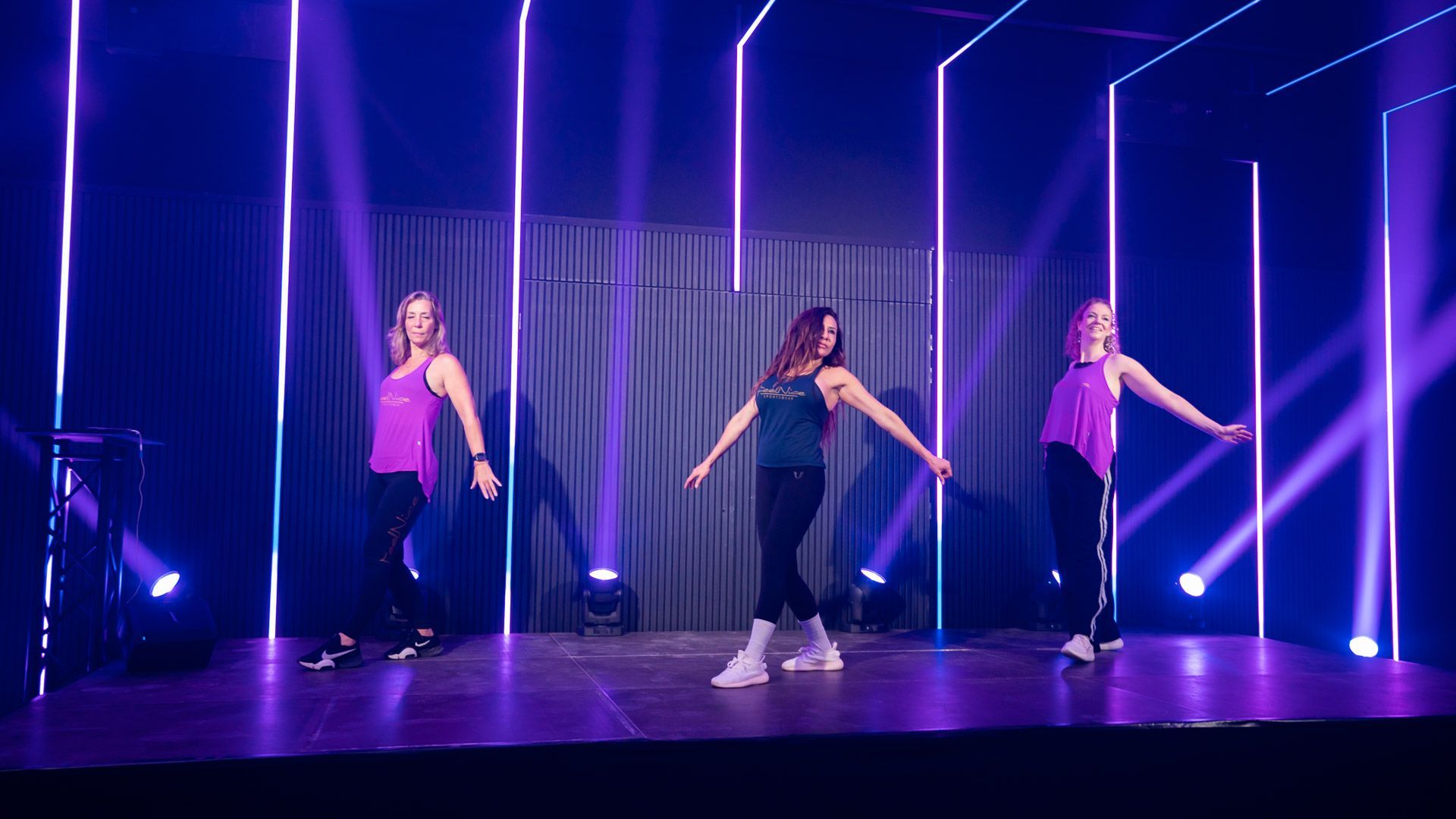 3 Vrouwen dansen op een podium als een groepsles in een sportschool.
