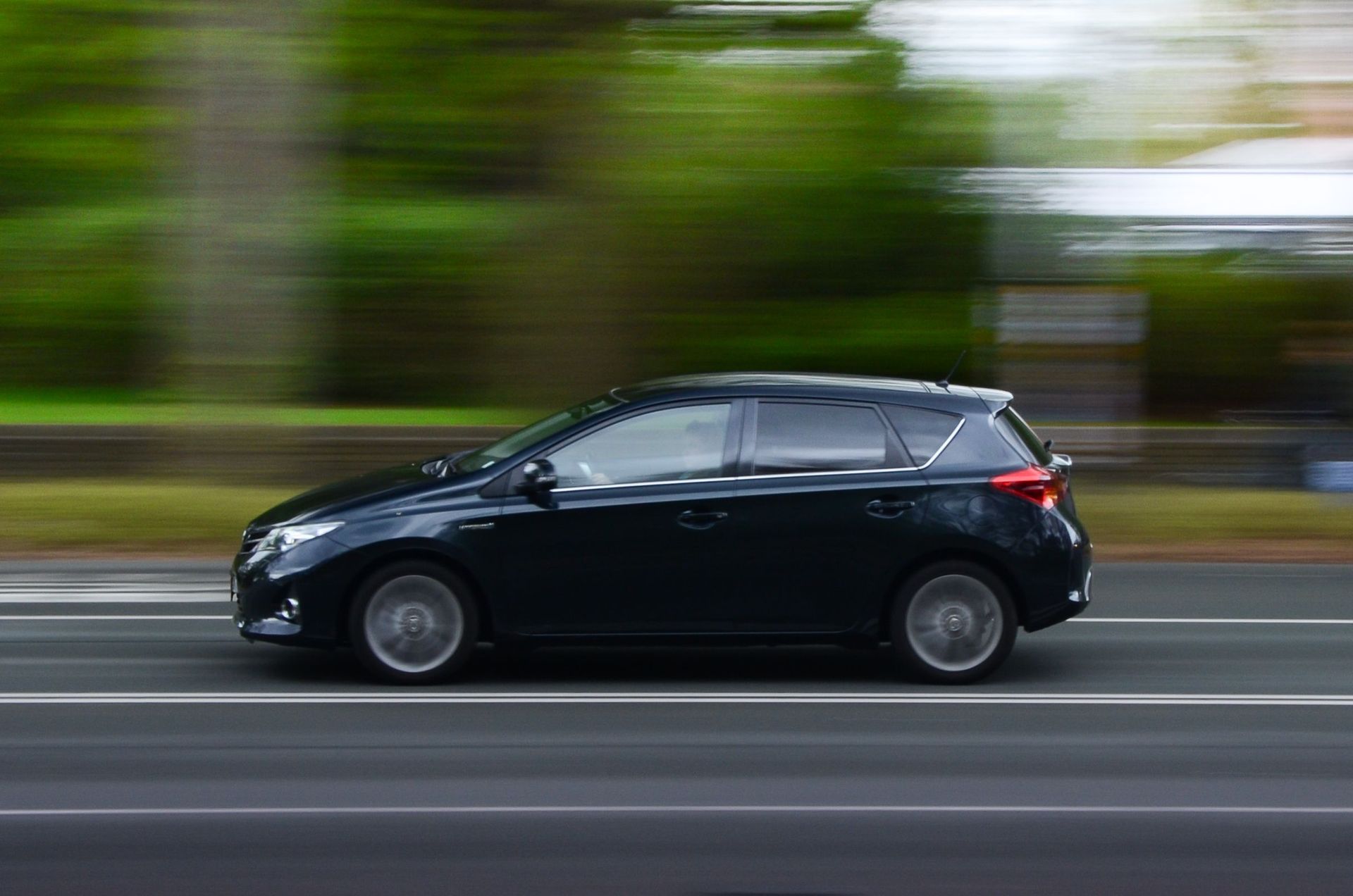 Hatchback car accelerating past a blurred roadside. | H & H Auto Service