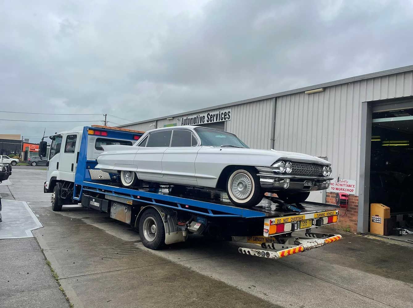 A White Car is Being Towed by a Tow Truck — Quick Hitch Towing & Tilt Tray Services Illawarra in Tullimbar, NSW