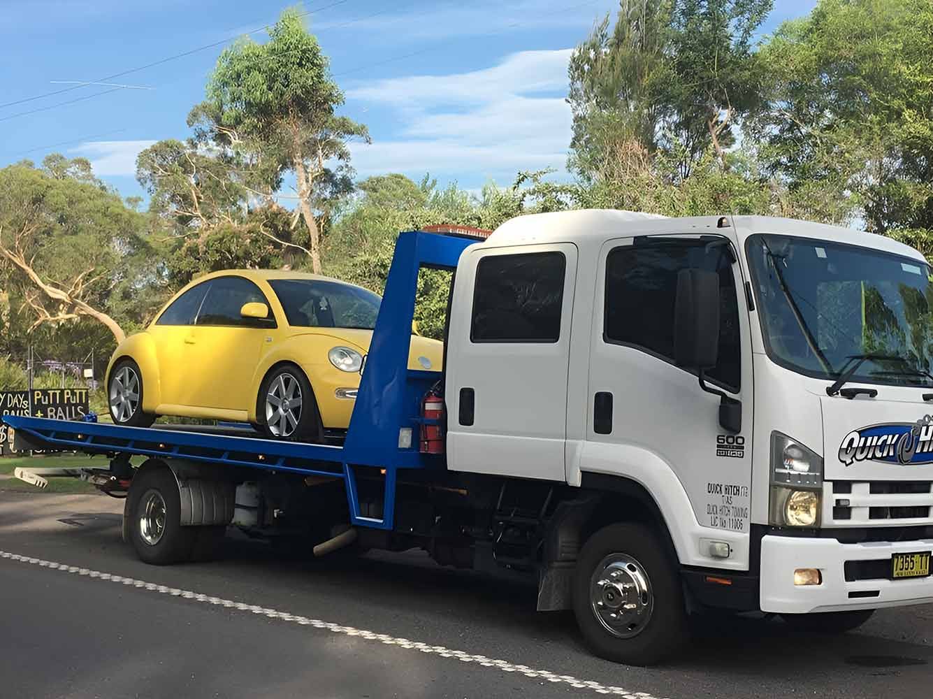 A Tow Truck With a Car on the Back is Parked Roadside — Quick Hitch Towing & Tilt Tray Services in Oak Flats, NSW