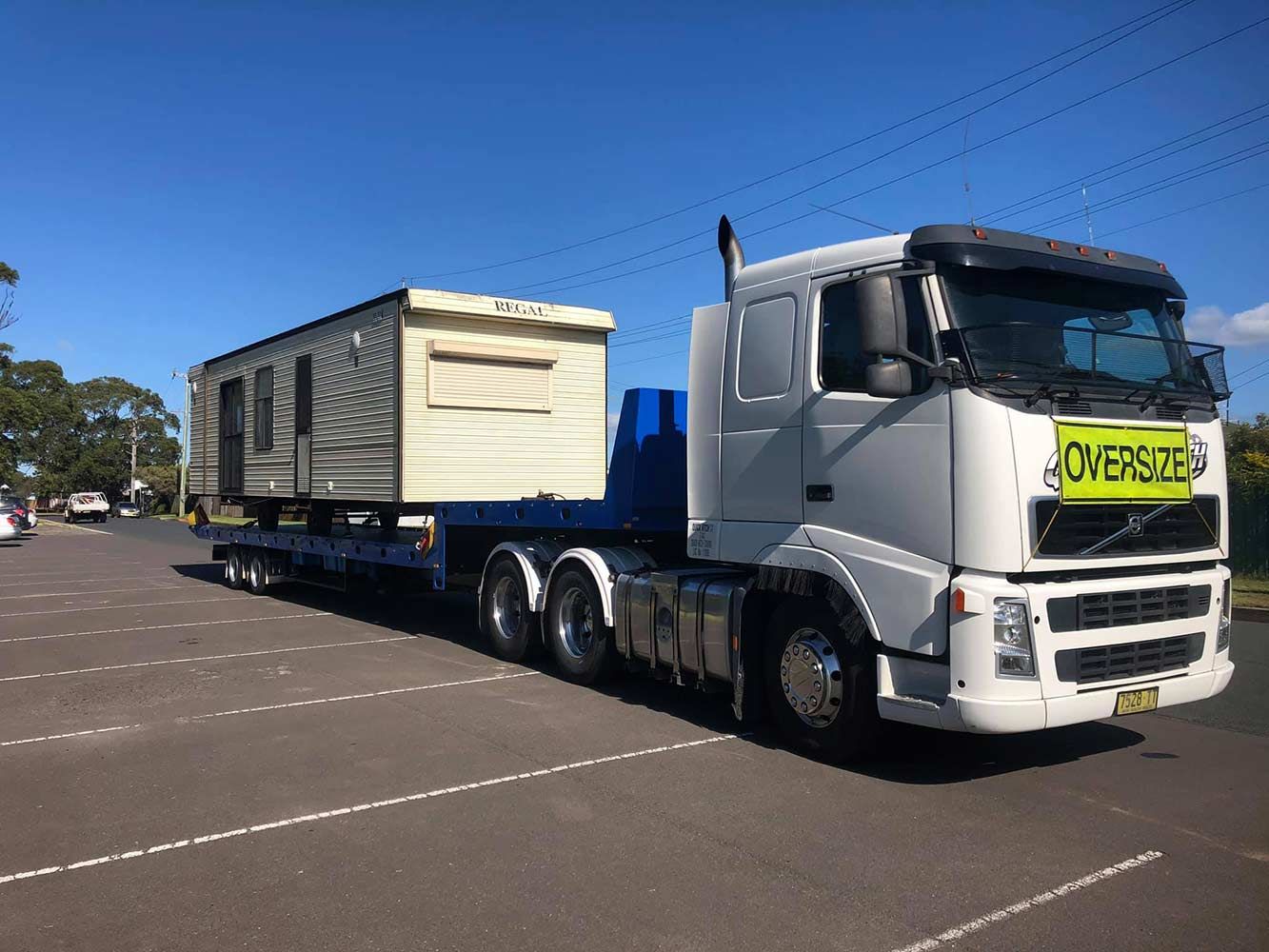 A White Truck is Carrying a Trailer With a House on It — Quick Hitch Towing & Tilt Tray Services Illawarra in Oak Flats, NSW
