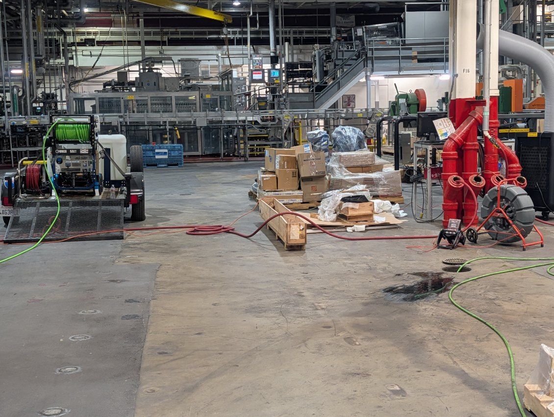 Industrial factory floor with pallets, boxes, and red machinery amid equipment and cables