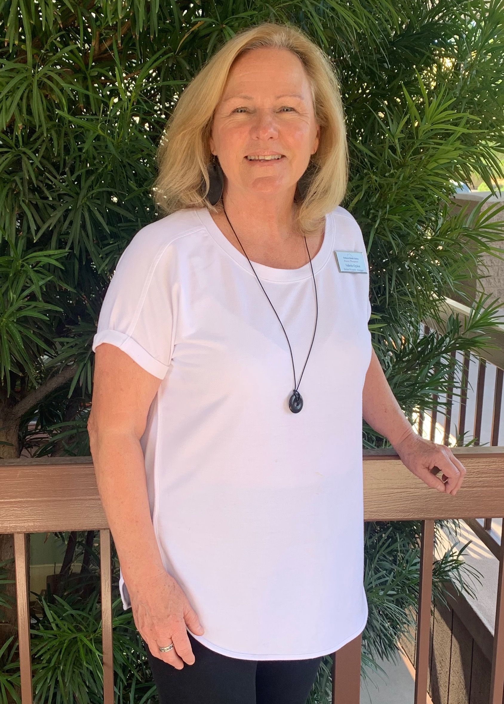 A woman in a white shirt and black pants is standing next to a railing.