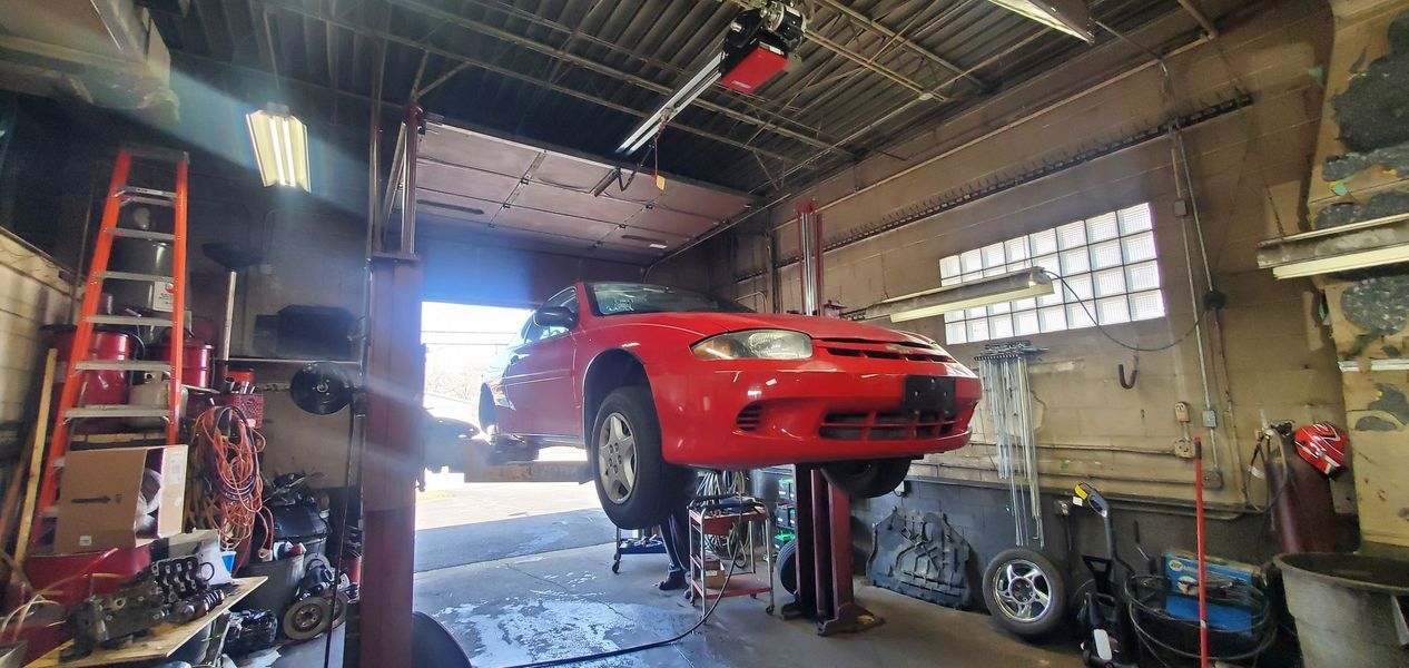A red car is sitting on a lift in a garage.
