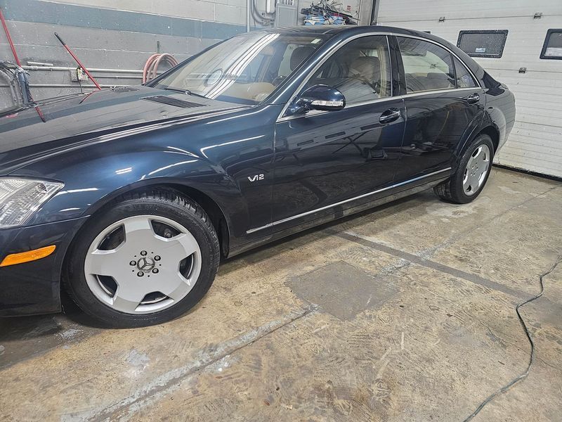 A black mercedes benz s class is parked in a garage.