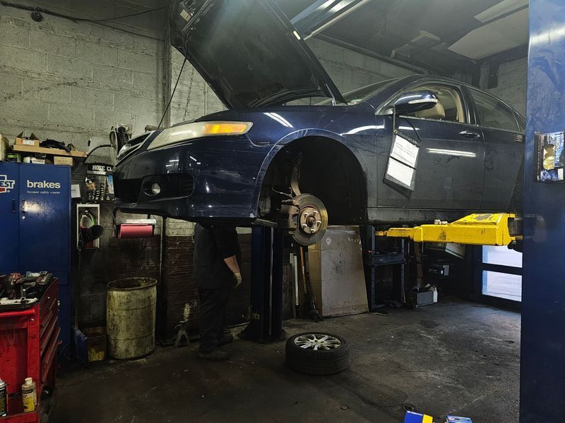 A blue car is sitting on a lift in a garage.