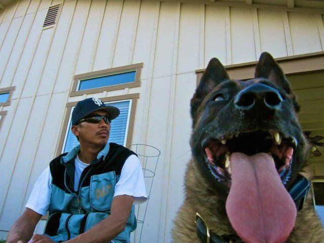 a man sitting next to a dog with its tongue out