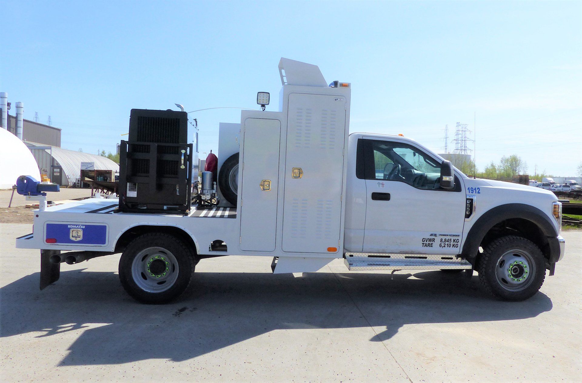 White service truck with equipment in a paved lot.