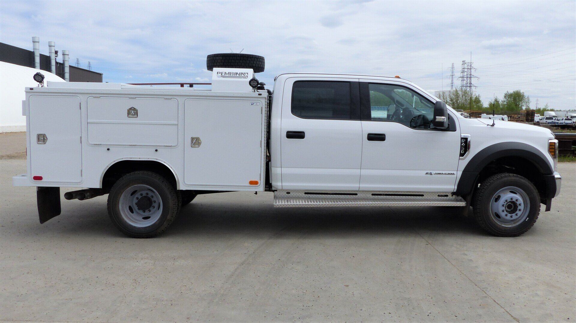 A white Ford service truck with a utility body and dual rear wheels parked outdoors.