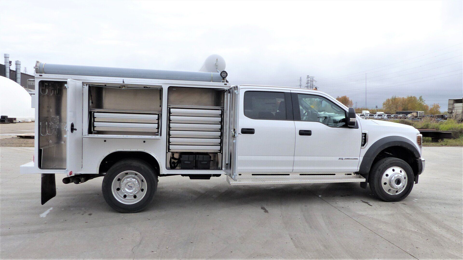 A white truck is parked in a parking lot with its doors open.