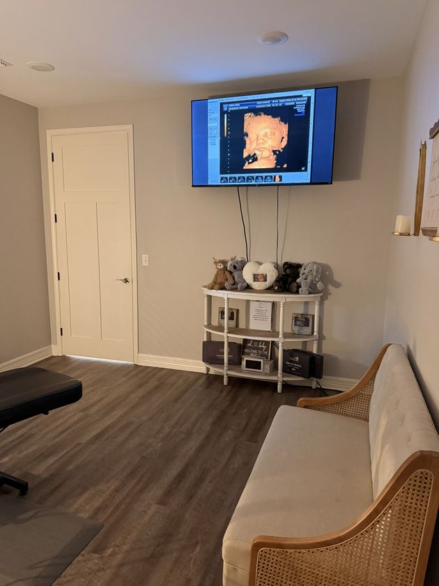 Living room with wall-mounted TV, white console table, beige sofa, and dark wood floor.