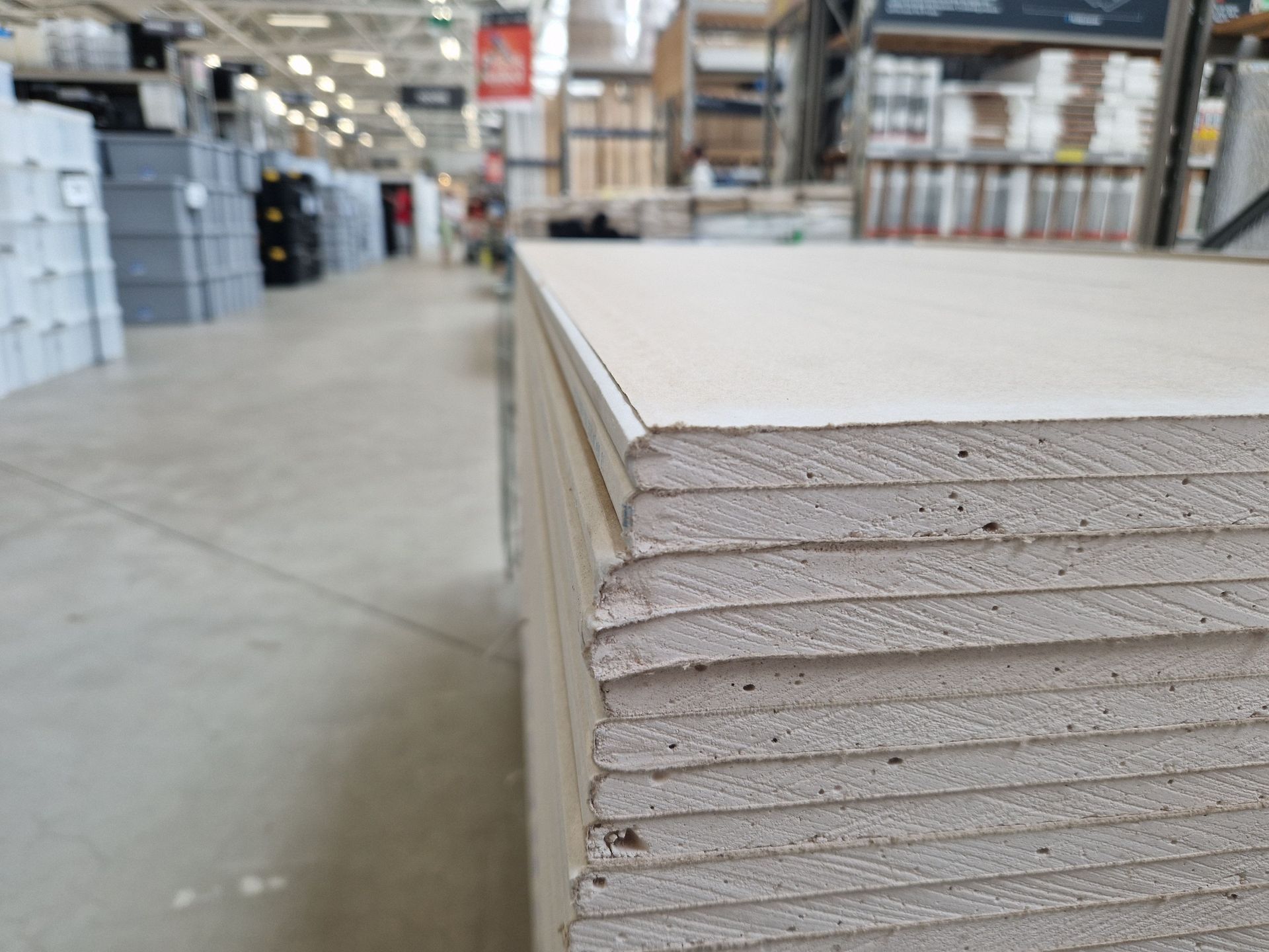 Stacked white drywall panels in a warehouse aisle