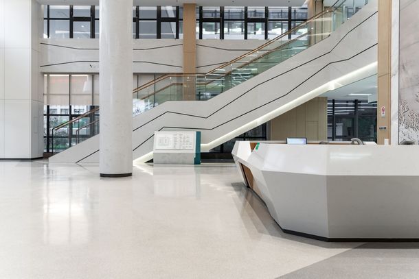 Bright modern atrium with escalators, white floors, large windows, and a reception desk Bright modern atrium with escalators, white floors, large windows, and a reception desk