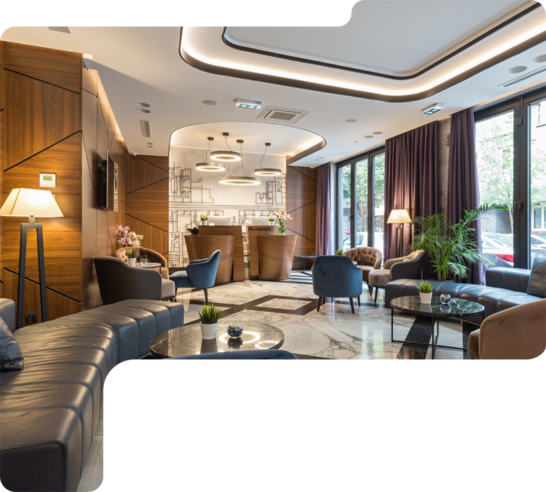 Elegant hotel lounge with leather seating, marble floor, warm lighting, and large windows overlooking greenery