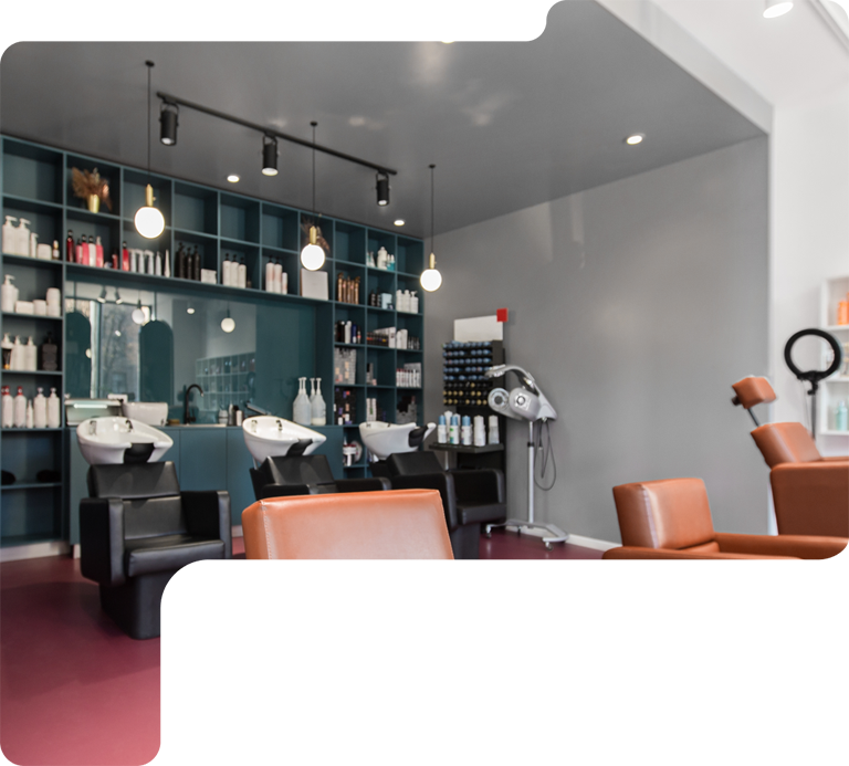 Modern hair salon interior with black styling chairs, mirrors, shelves, and hanging lights