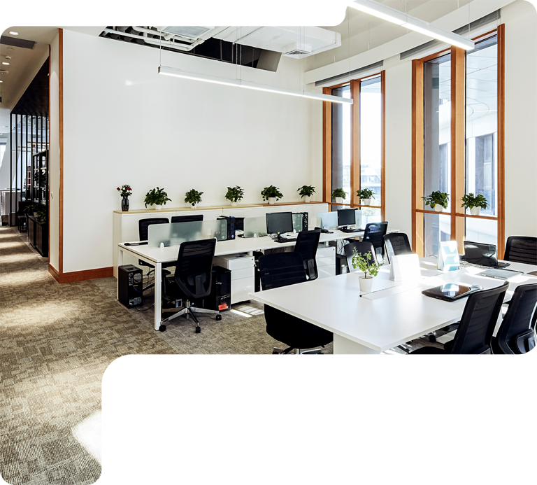 Modern open-plan office with desks, computers, black chairs, and large windows