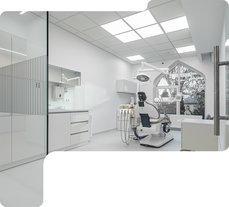 Bright modern dental clinic with a patient chair, overhead lamp, cabinets, and glass partitions.