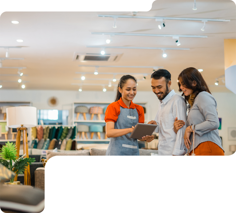 Three people smiling and looking at a clipboard in a bright retail store