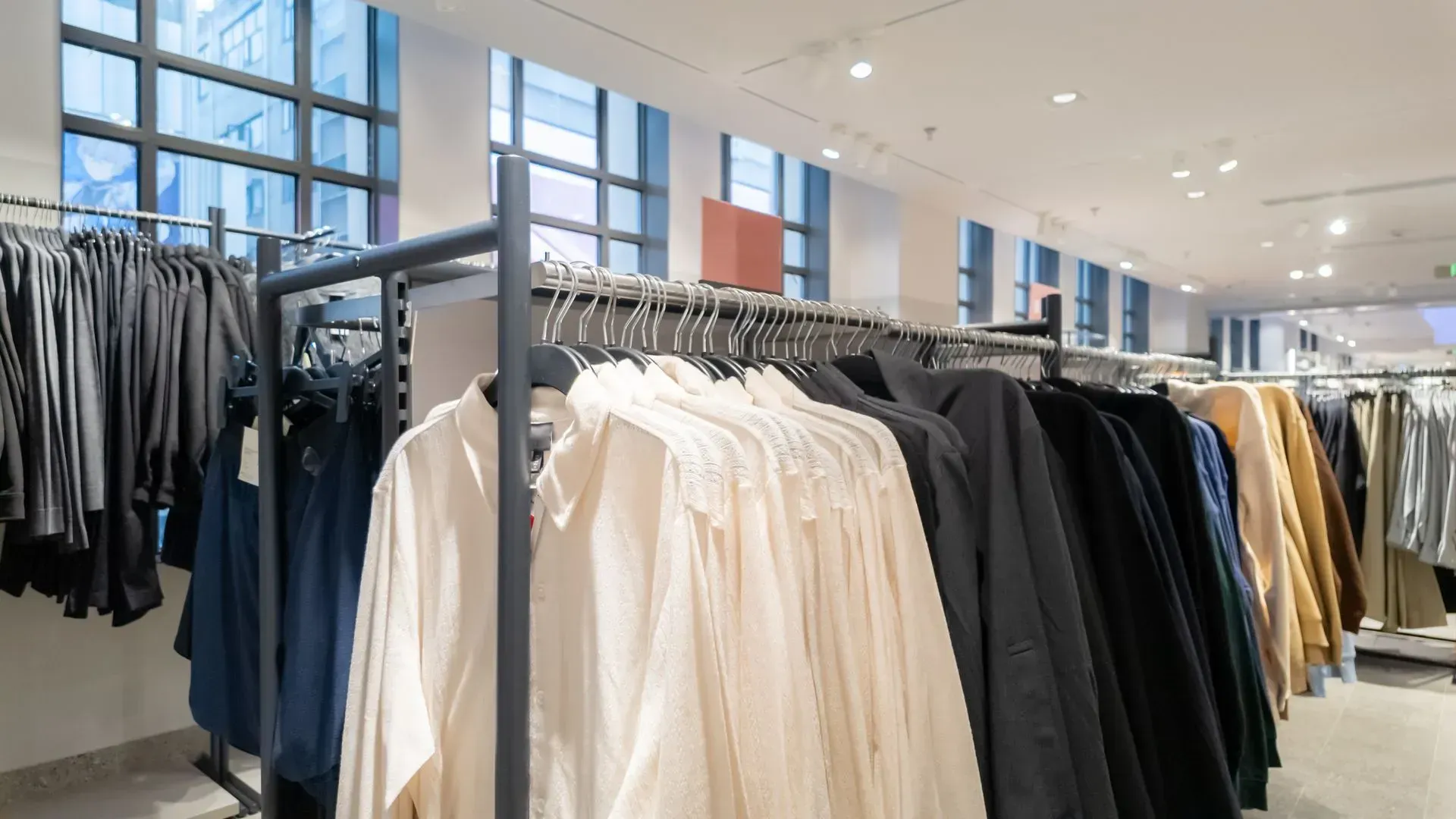 Clothing racks with jackets and shirts in a bright retail store interior