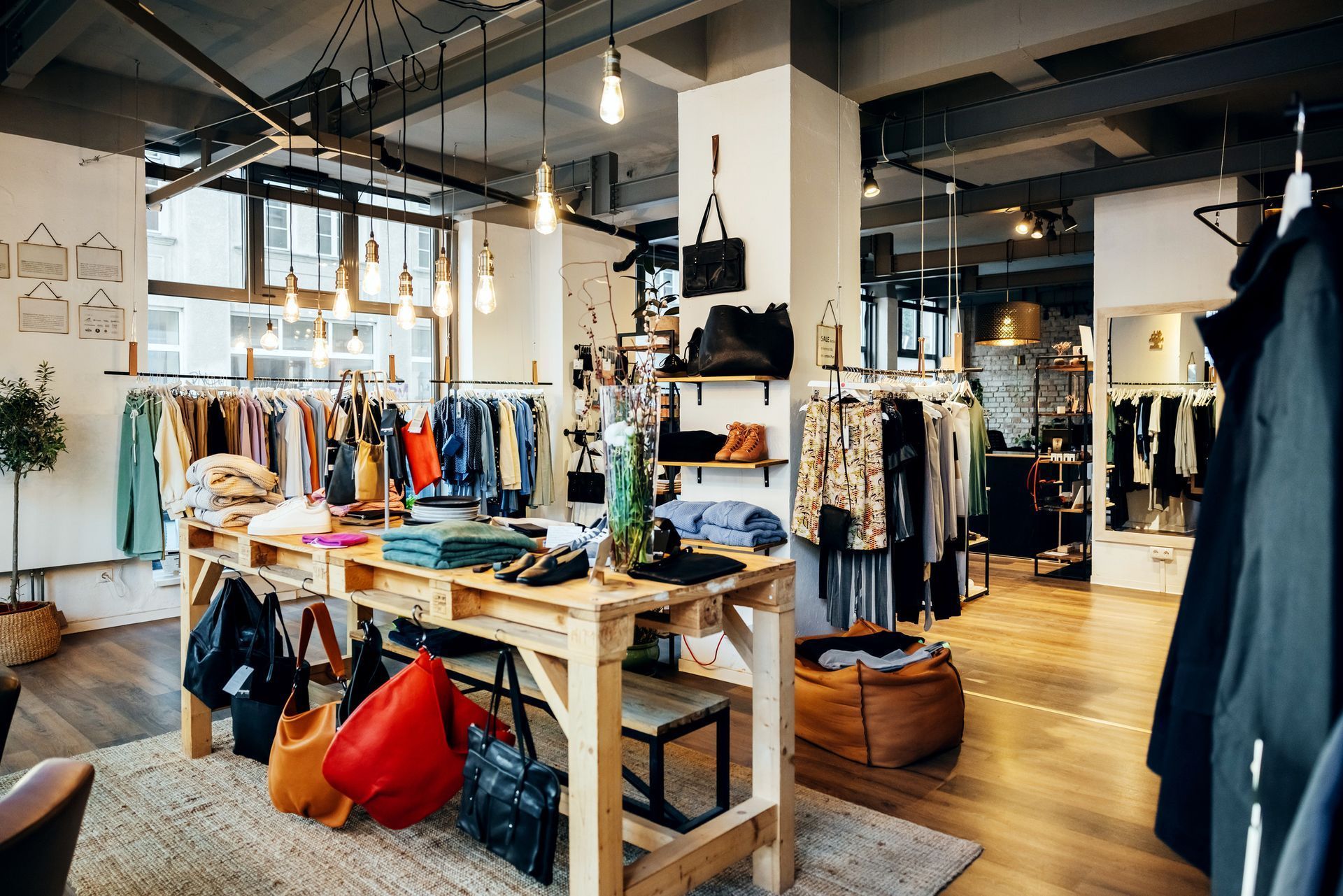 Clothing boutique interior with racks of apparel, tables, and warm lighting on wooden floors