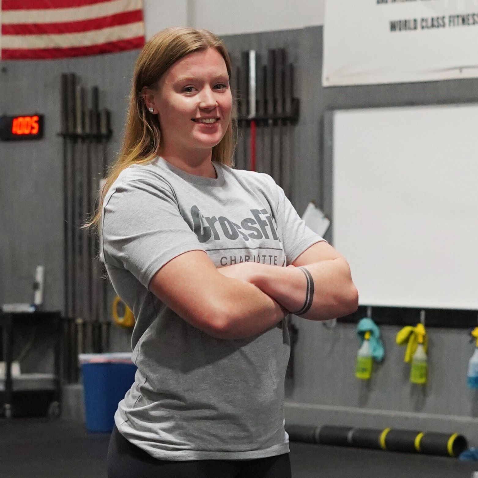 A woman wearing a crossfit shirt stands with her arms crossed