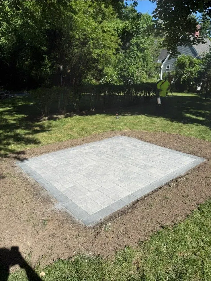 Rectangular concrete slab set in a grassy yard with trees and a house in the background.