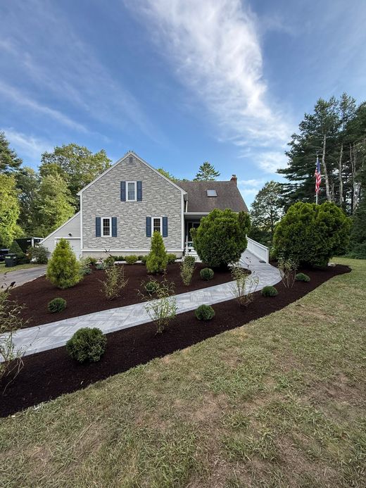Suburban house with landscaped flower bed of yellow blooms and shrubs along a curved lawn edge