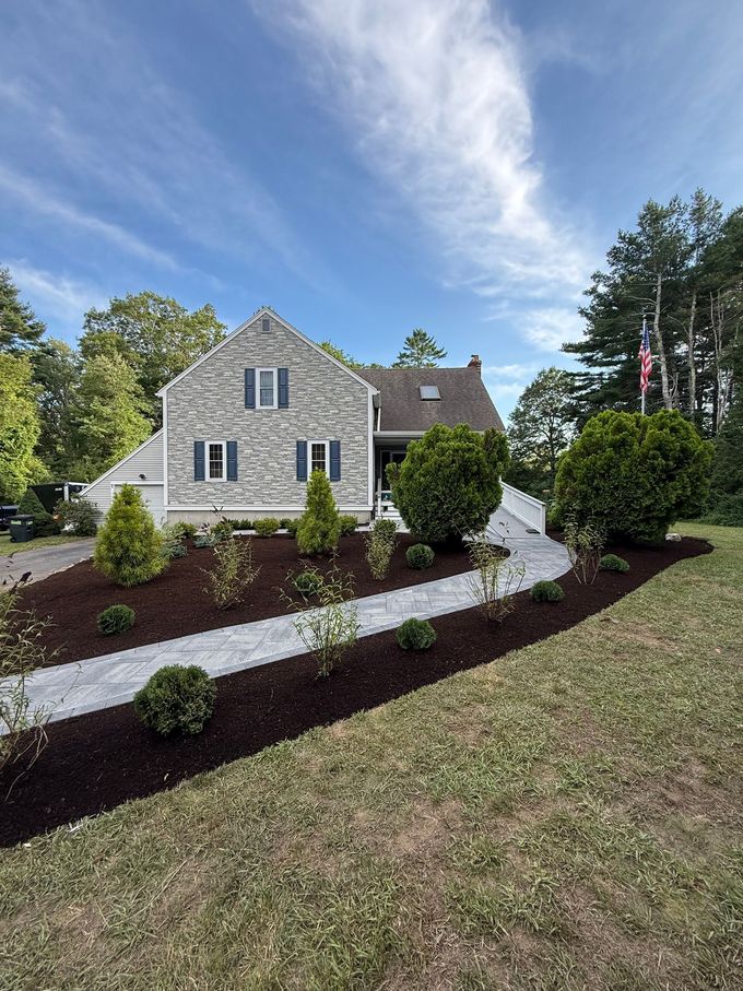 Suburban house with landscaped flower bed of yellow blooms and shrubs along a curved lawn edge