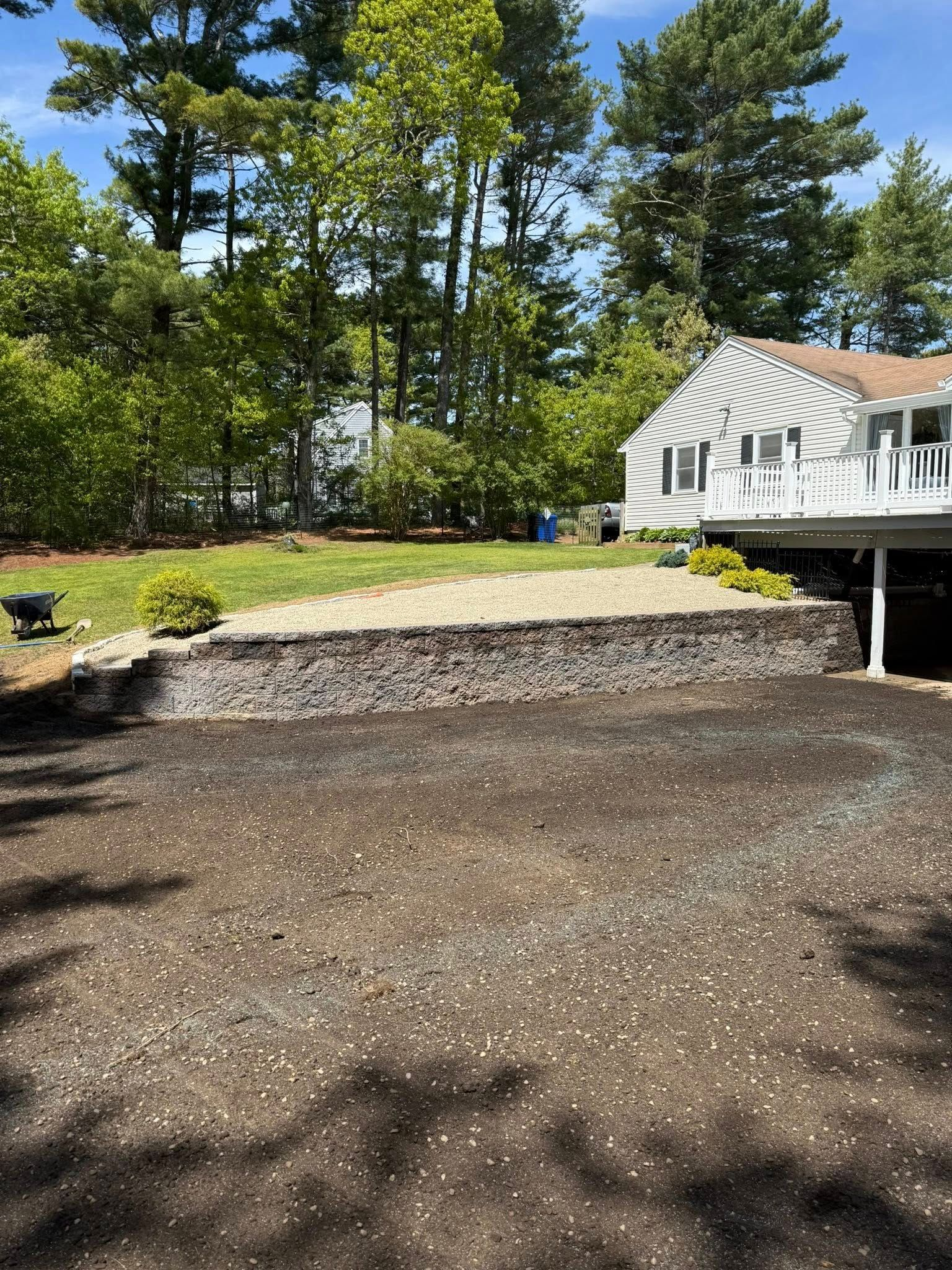 Curved stone retaining wall with lush green lawn and landscaped shrubs in a sunny garden