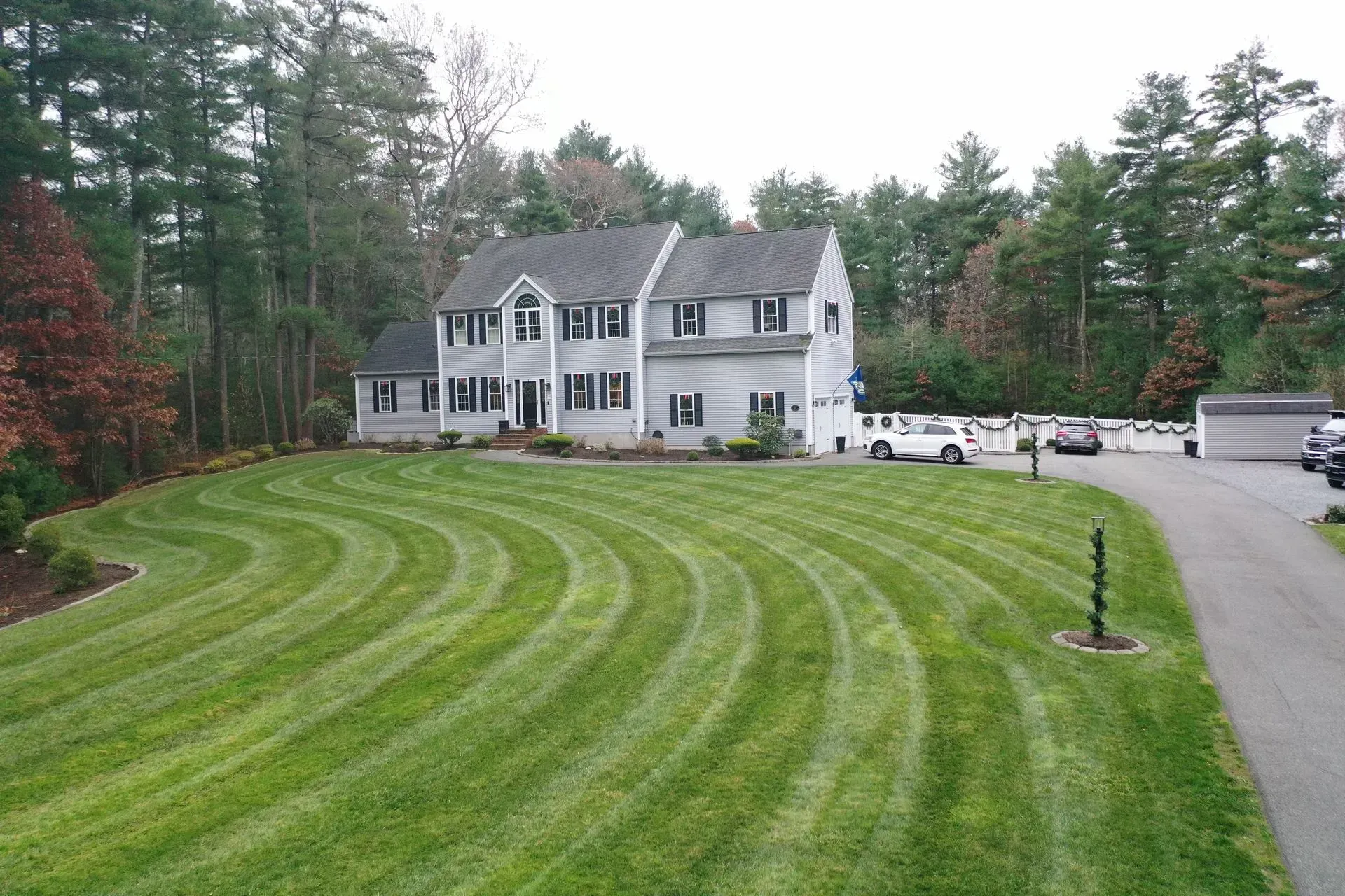 Person mowing a green lawn beside a gravel path with small shrubs