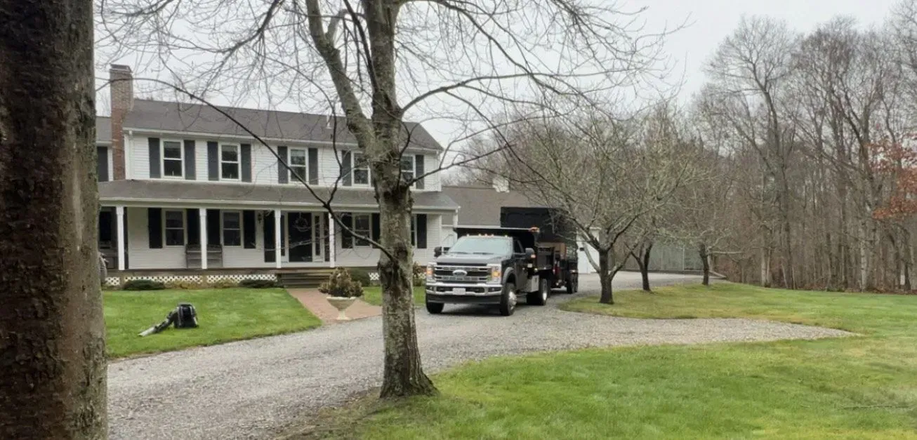 Suburban house with a white truck parked in the driveway and a large tree in front