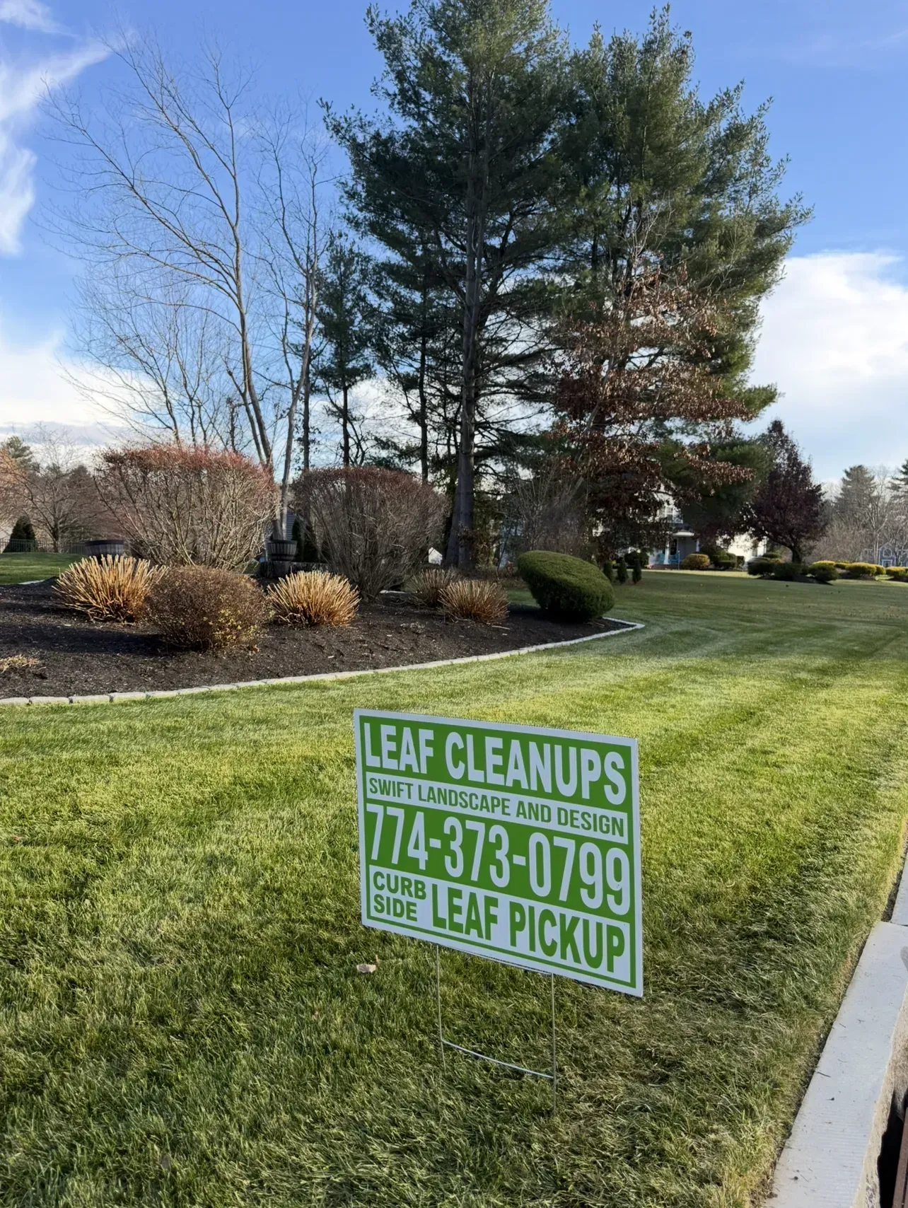 Lawn sign for “Leaf Cleanups,” advertising landscaping services with a phone number in a suburban yard.