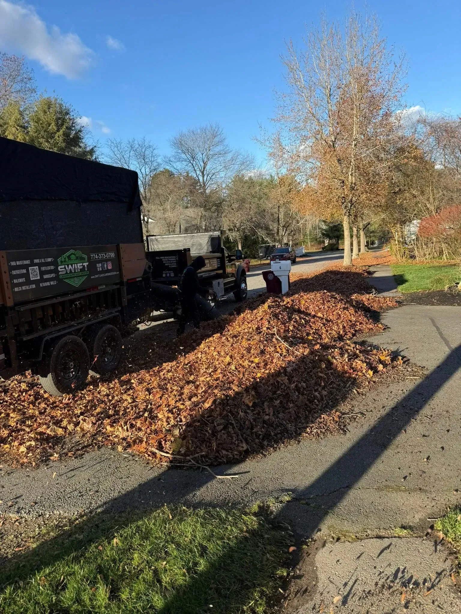 Leaves piled beside a truck on a gravel driveway in autumn.